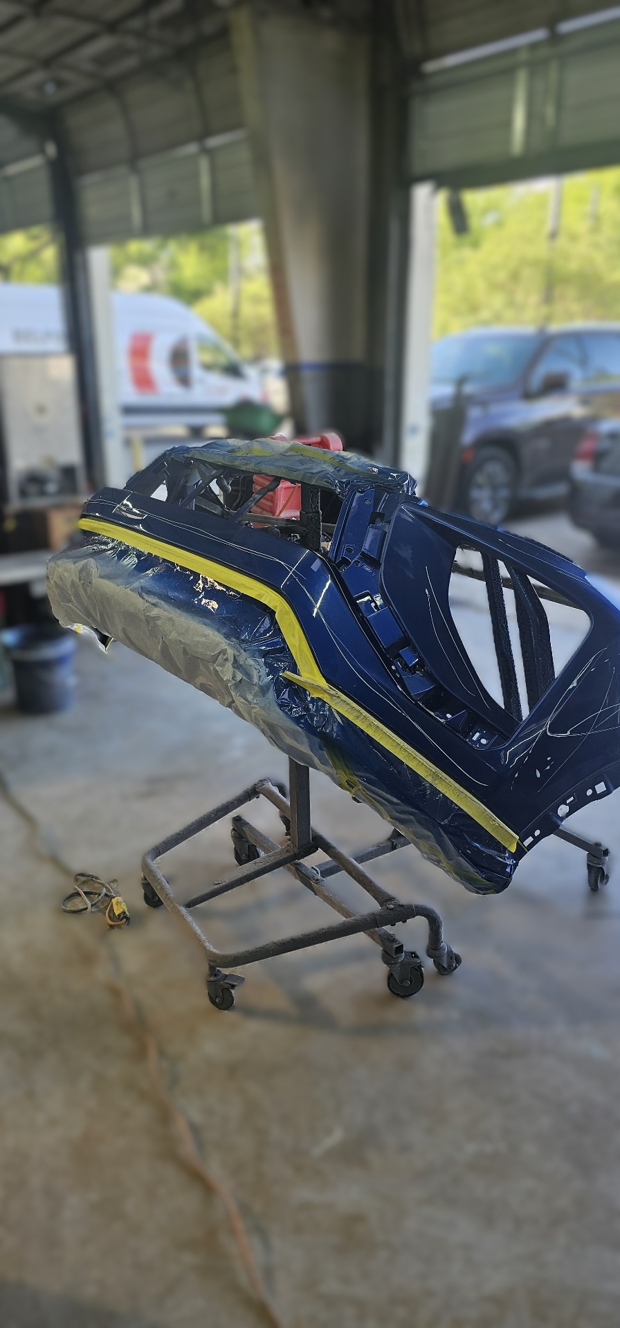 Vehicle panel masked and prepped in deep blue paint at Mission Body Shop